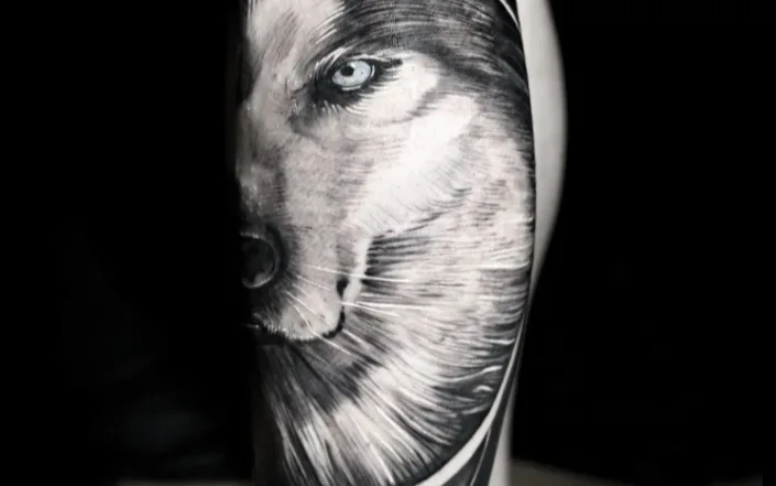 A black-and-grey realism tattoo of a wolf's head on a client's lower leg, representative of Nathaly Hernandez's blackwork style — cropped to the tattoo only.