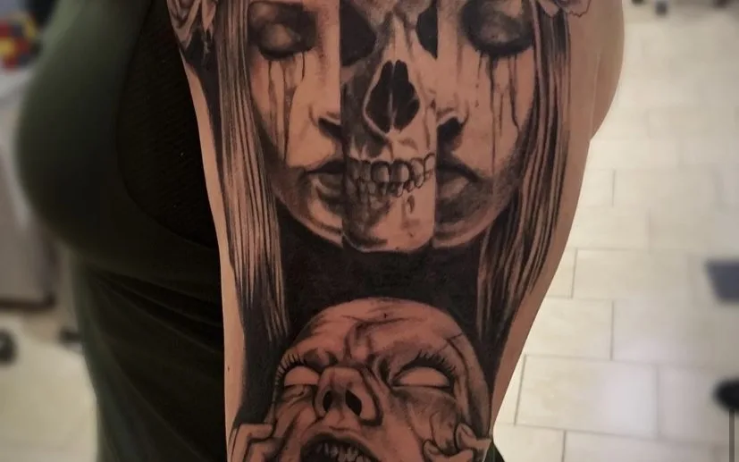 A black-and-grey half-sleeve tattoo combining a split face/skull portrait with roses and a screaming mask motif, cropped to the tattoo only.